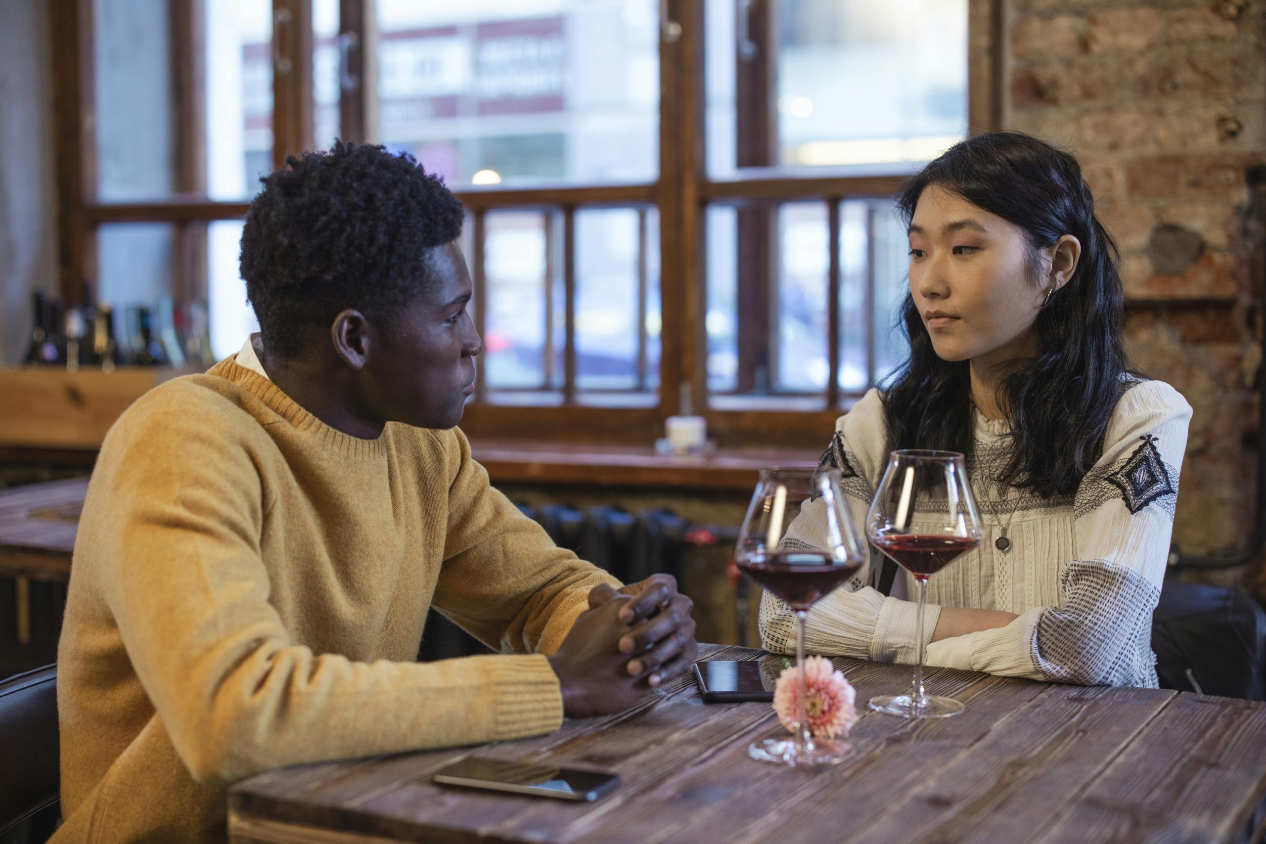 Un couple diversifié profitant de vin et d'une conversation dans un cadre de café rustique.