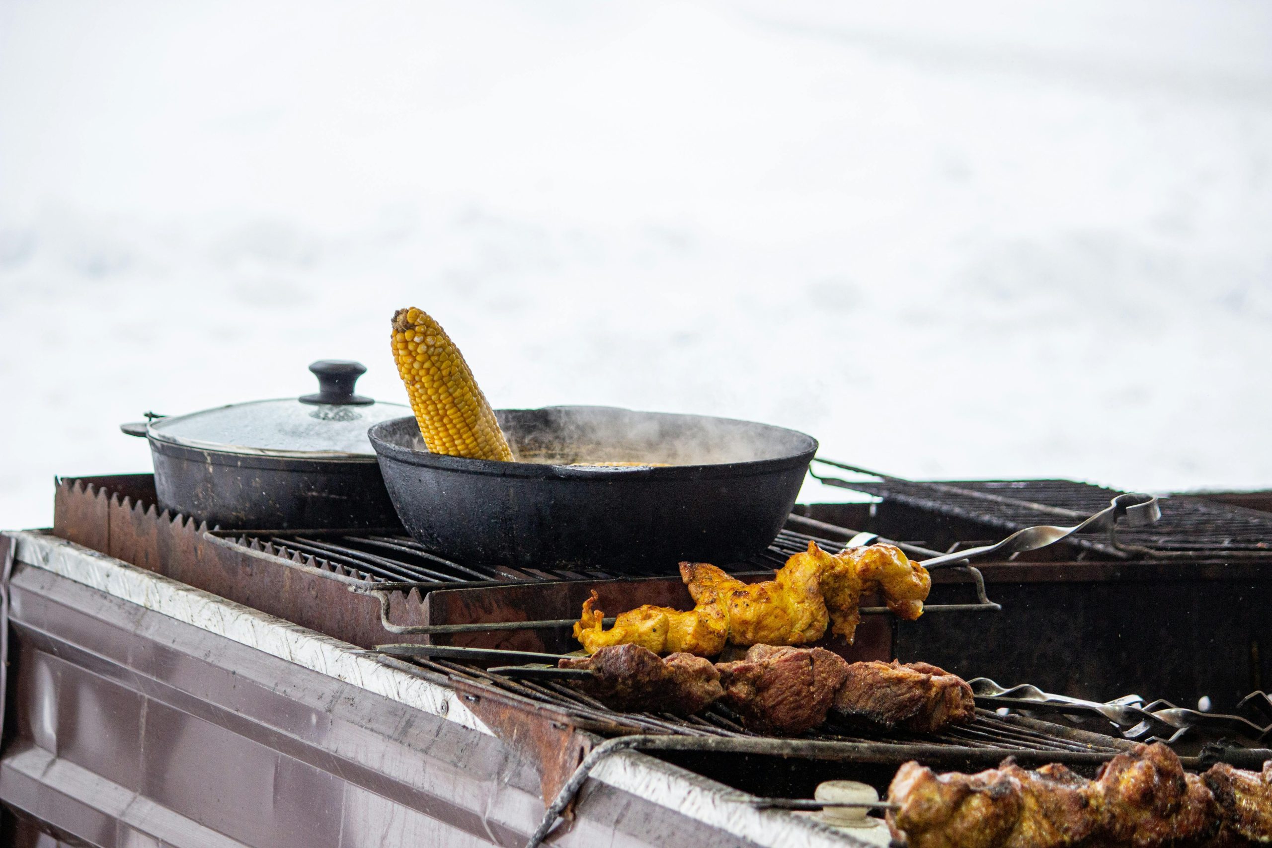 Outdoor grill scene avec du maïs et des brochettes de poulet, parfait pour les thèmes de barbecue.