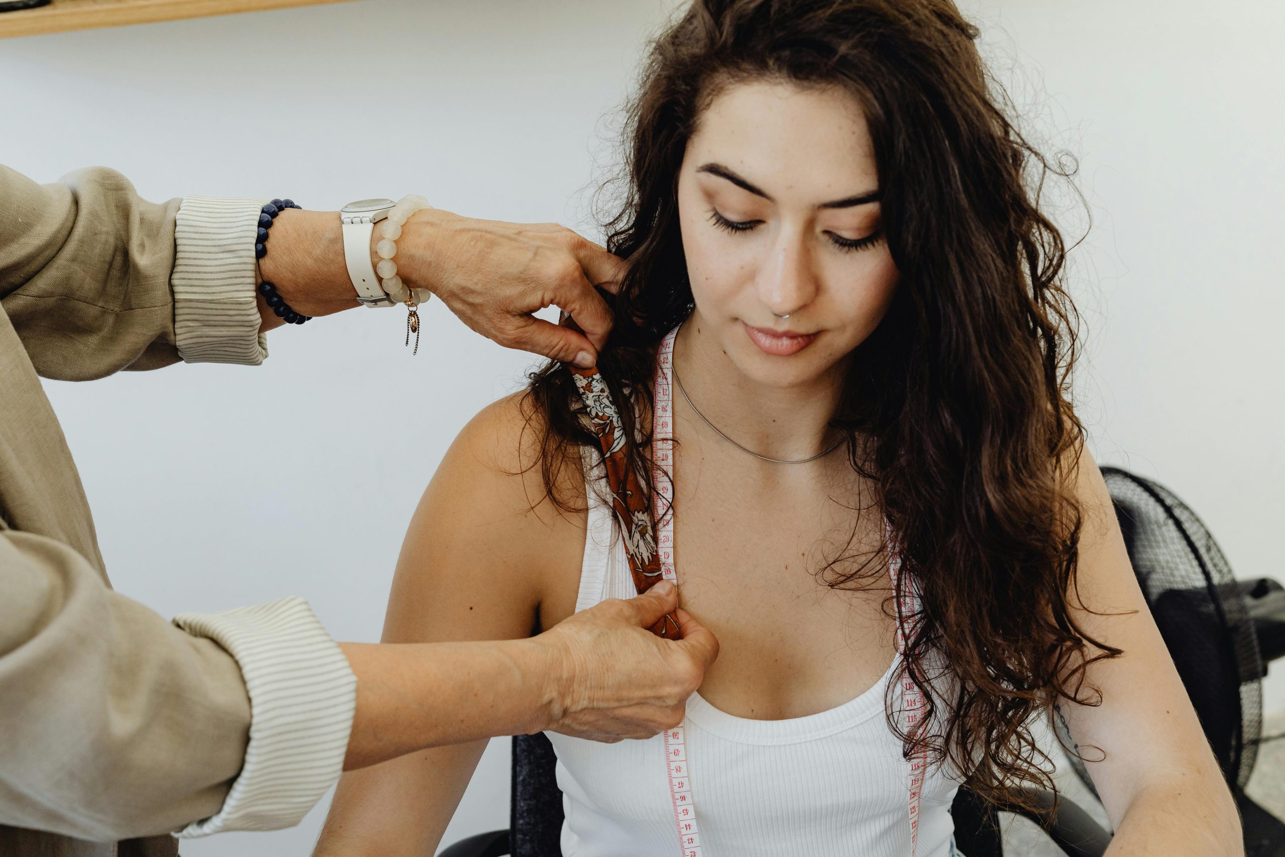 Young woman being measured with tape for tailoring indoors Une jeune femme mesurée avec un mètre pour la couture à l'intérieur