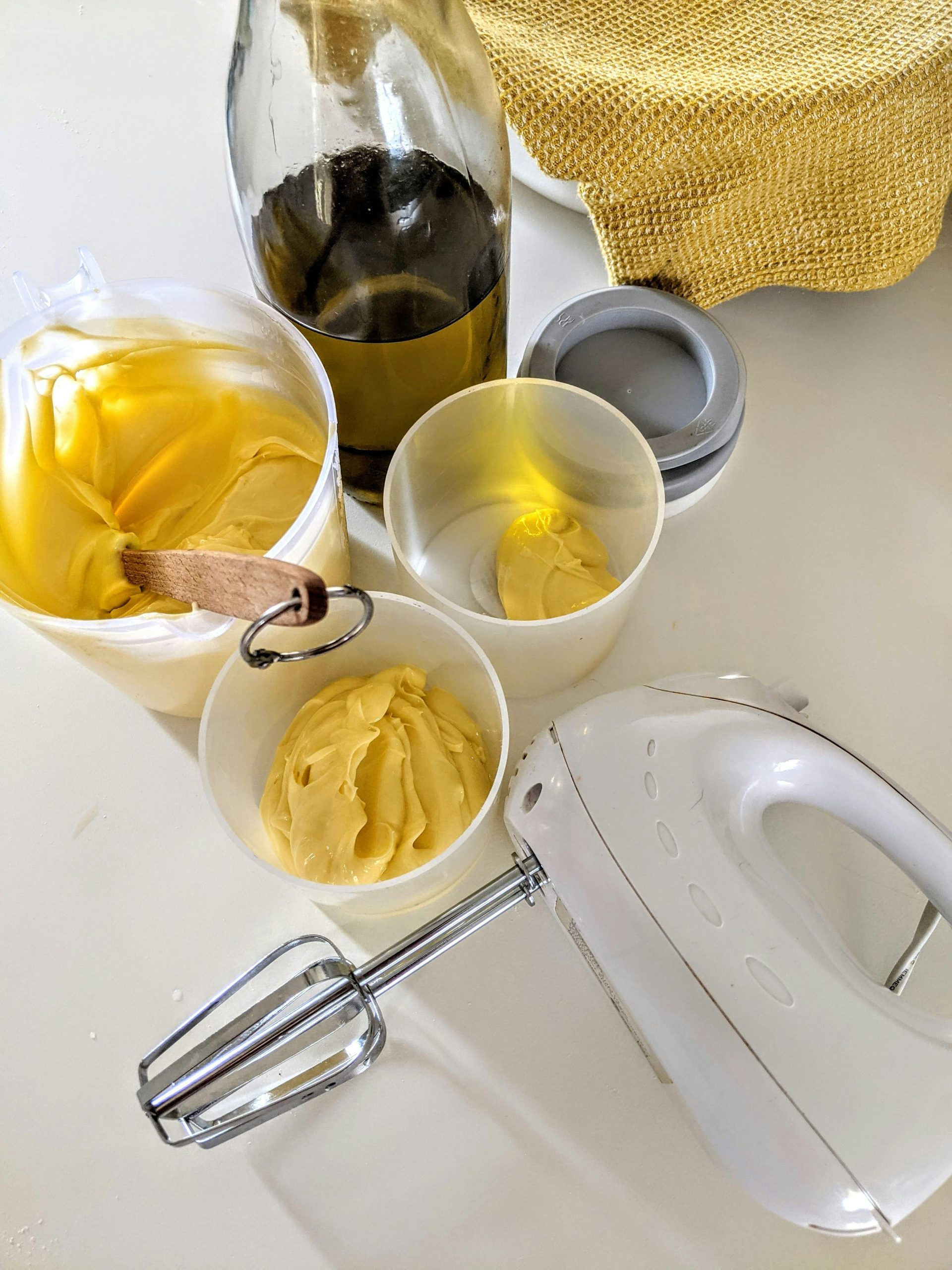 A high-angle view of cream being mixed with olive oil bottles and kitchen tools, perfect for cooking projects. Vue en plongée de la crème mélangée avec des bouteilles d'huile d'olive et des ustensiles de cuisine, parfaite pour les projets culinaires.
