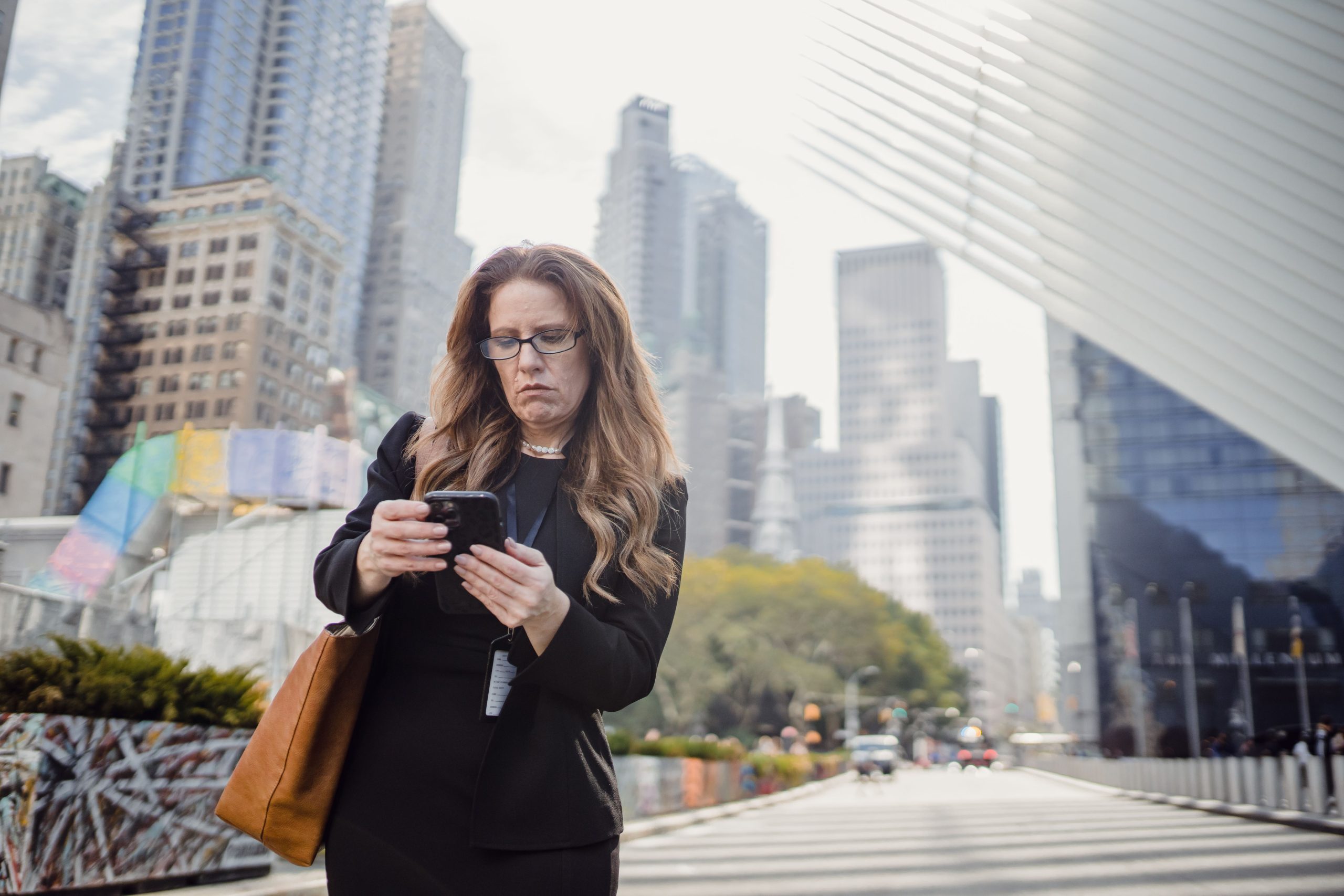 Businesswoman on phone in city street against modern skyscrapers. Femme d'affaires au téléphone dans une rue de la ville avec des gratte-ciel modernes en arrière-plan.