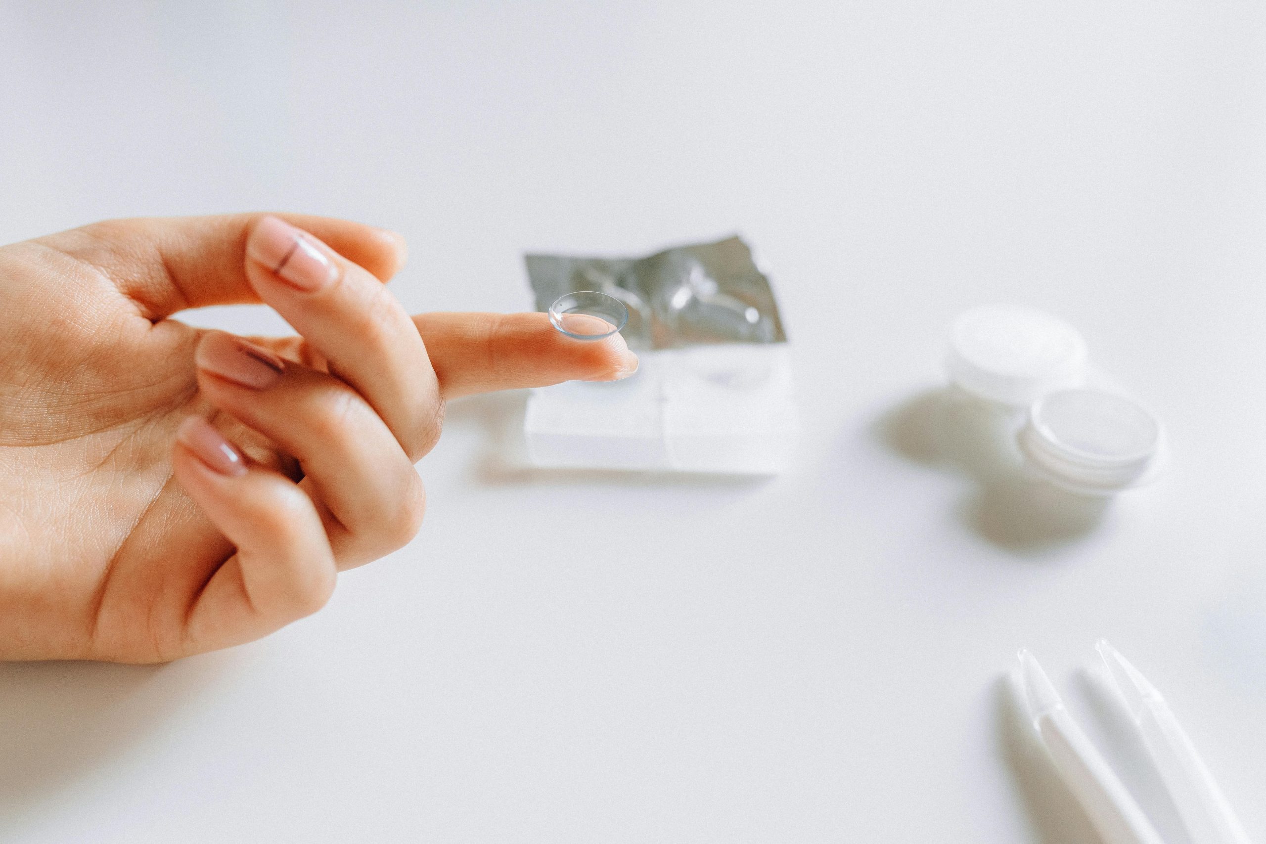 Close-up of hand handling contact lens, demonstrating eye care essentials. Gros plan d'une main manipulant une lentille de contact, démontrant les éléments essentiels des soins oculaires.
