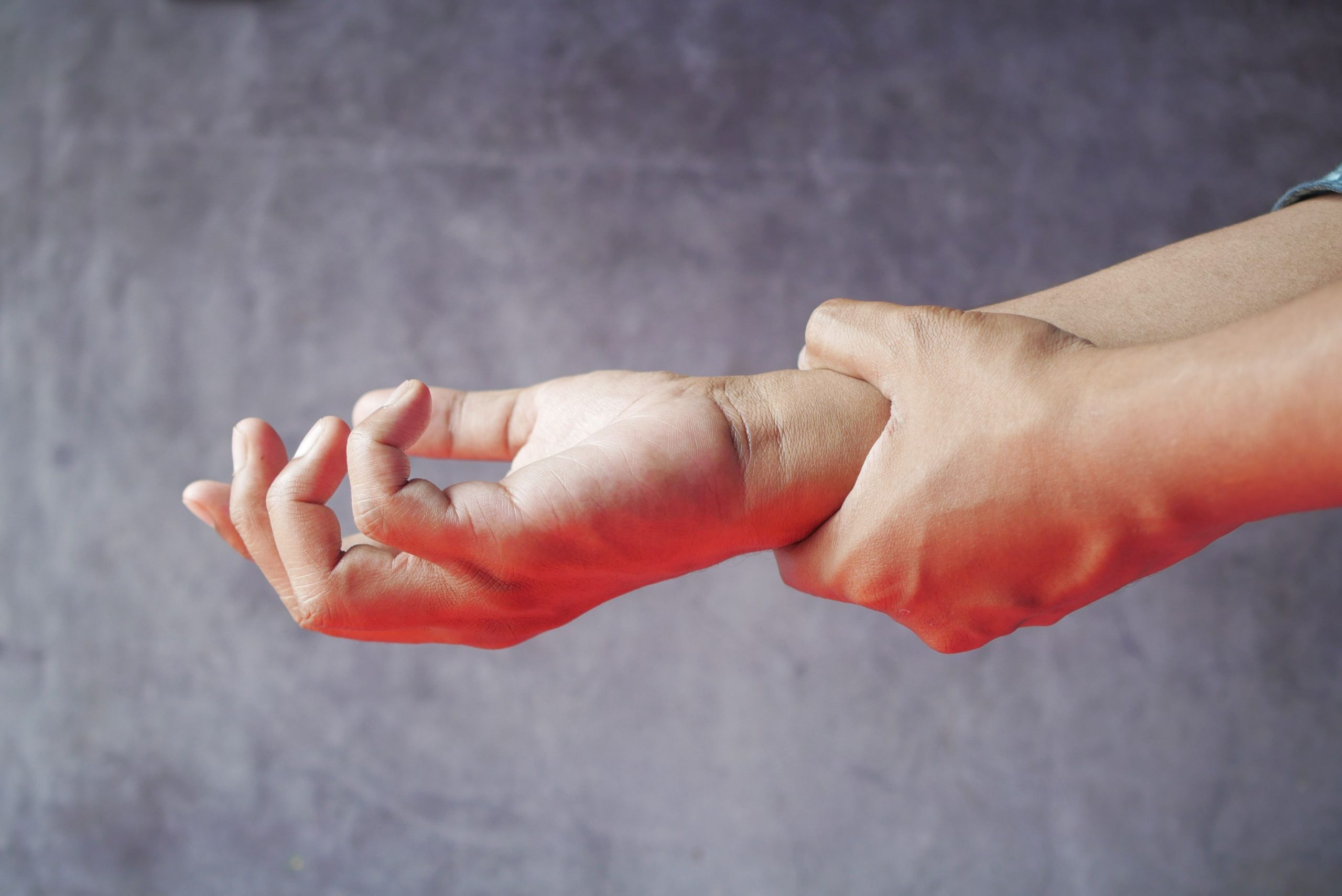 Close-up of hands, one grasping the other, symbolizing pain or discomfort. Gros plan de mains, l'une saisissant l'autre, symbolisant la douleur ou l'inconfort.