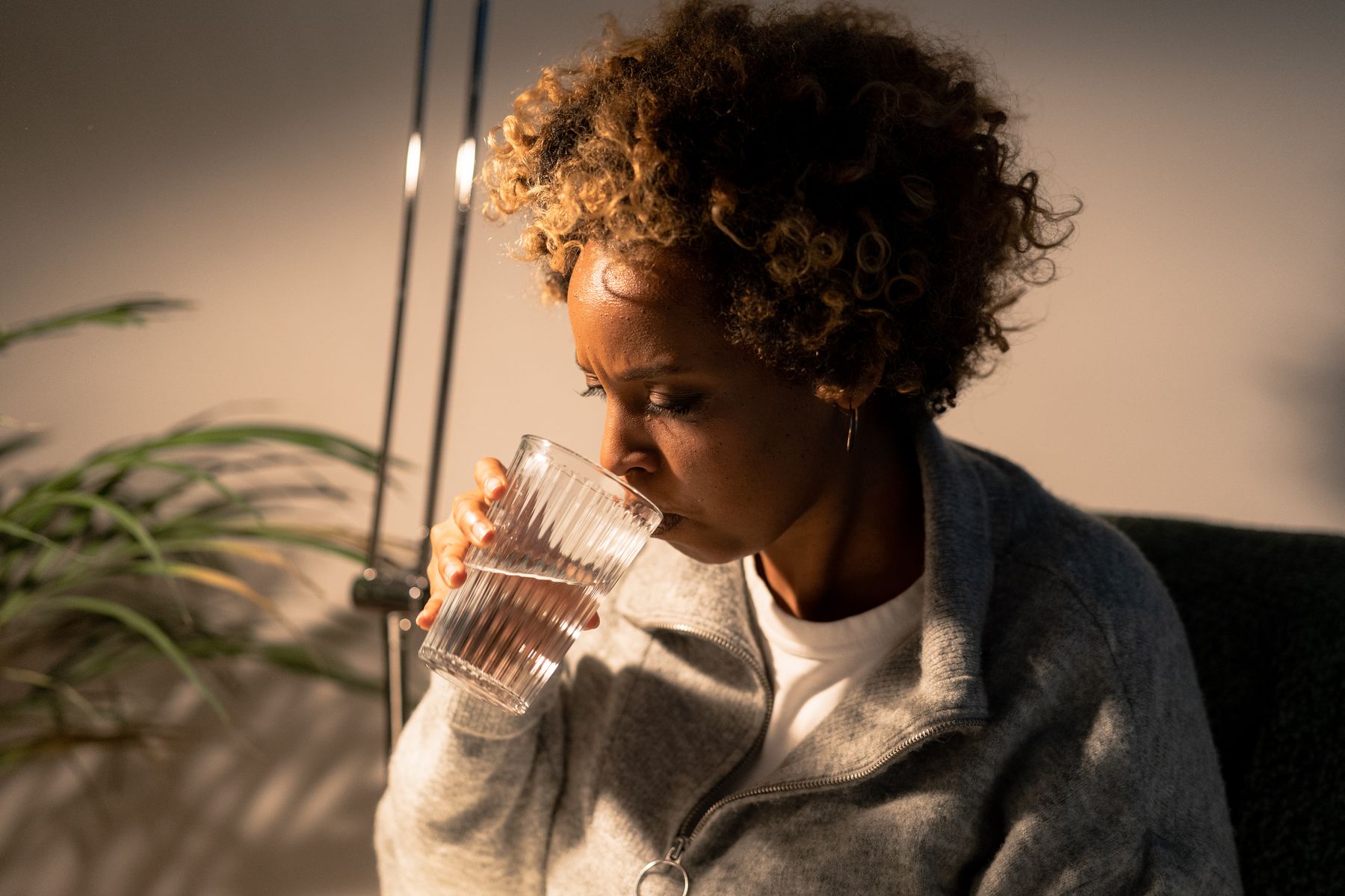 Femme savourant un verre d'eau à l'intérieur