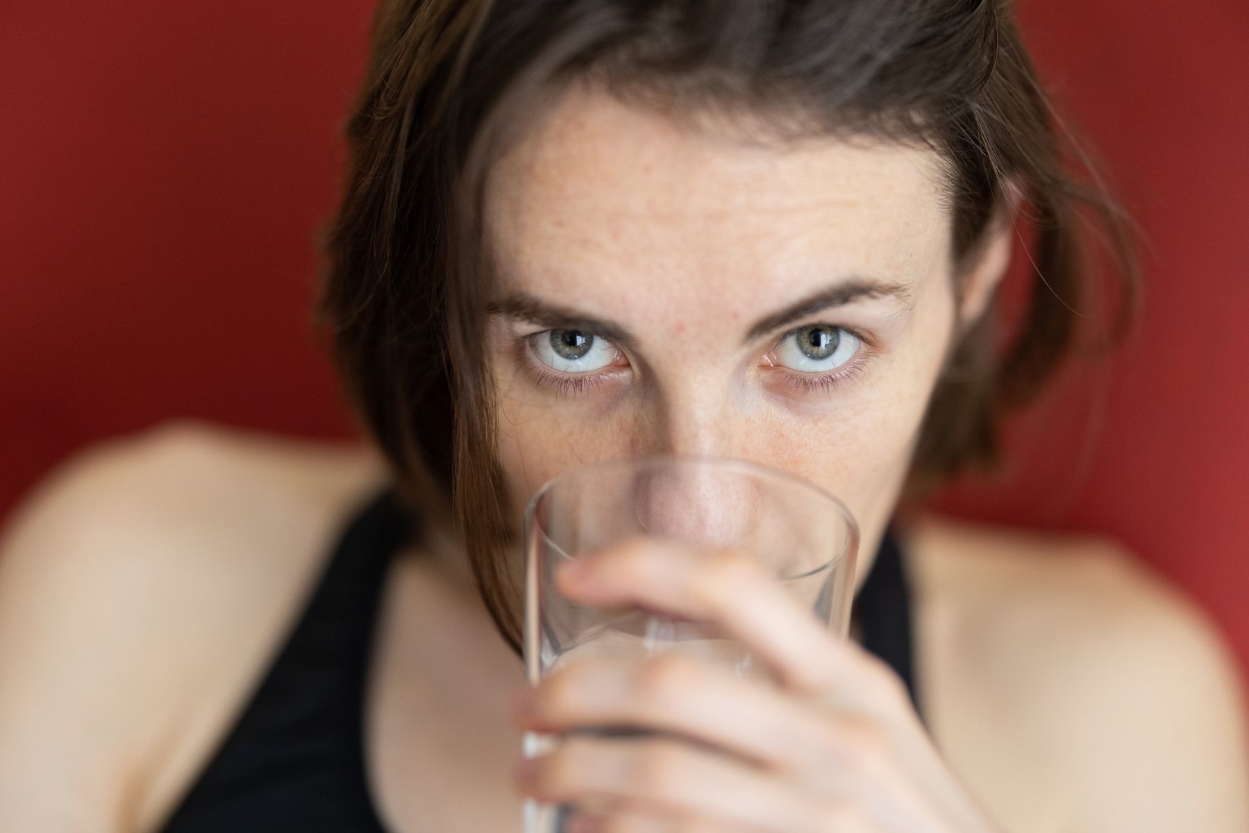 Jeune femme buvant lentement un verre d'eau