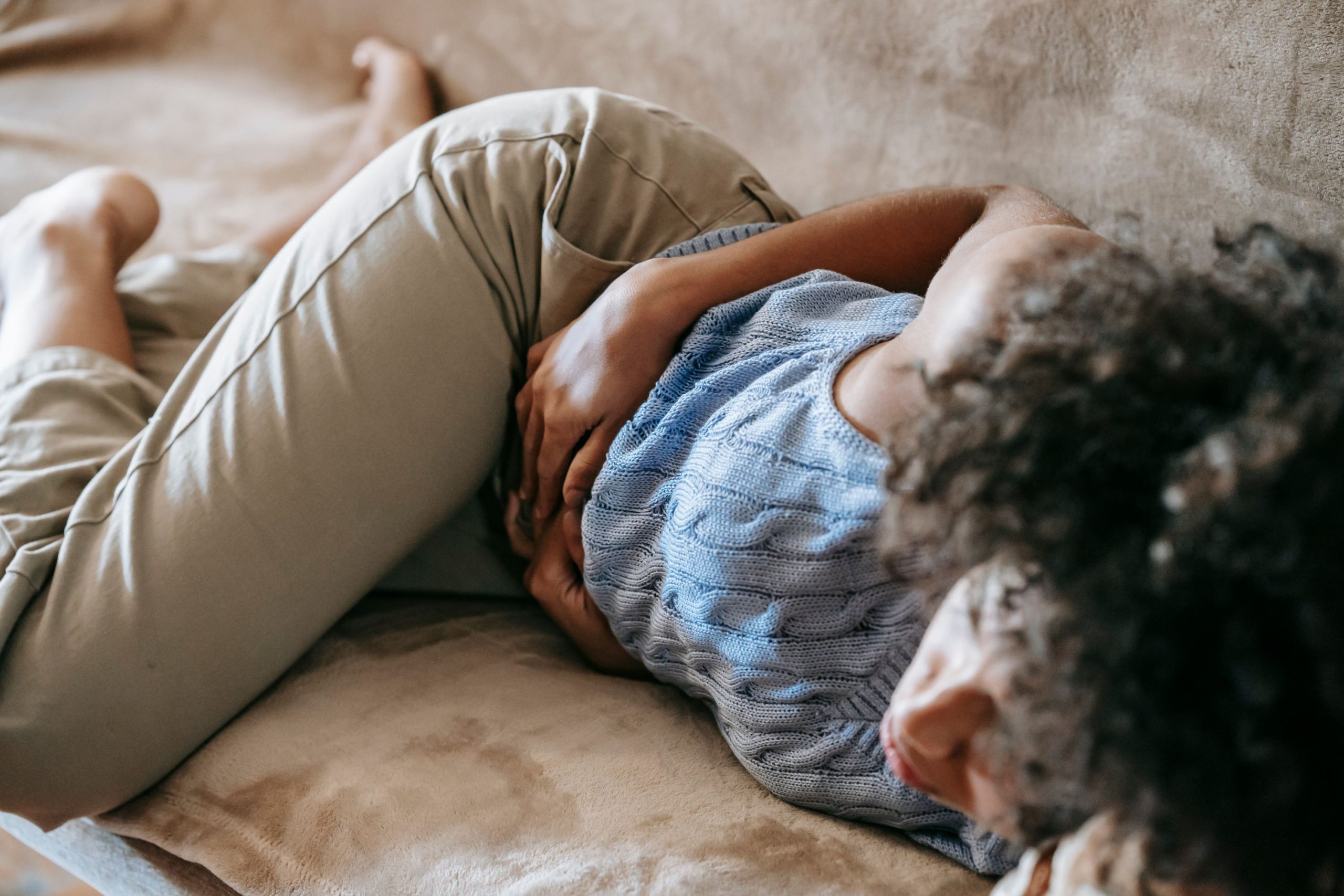 Femme allongée qui se tient le ventre