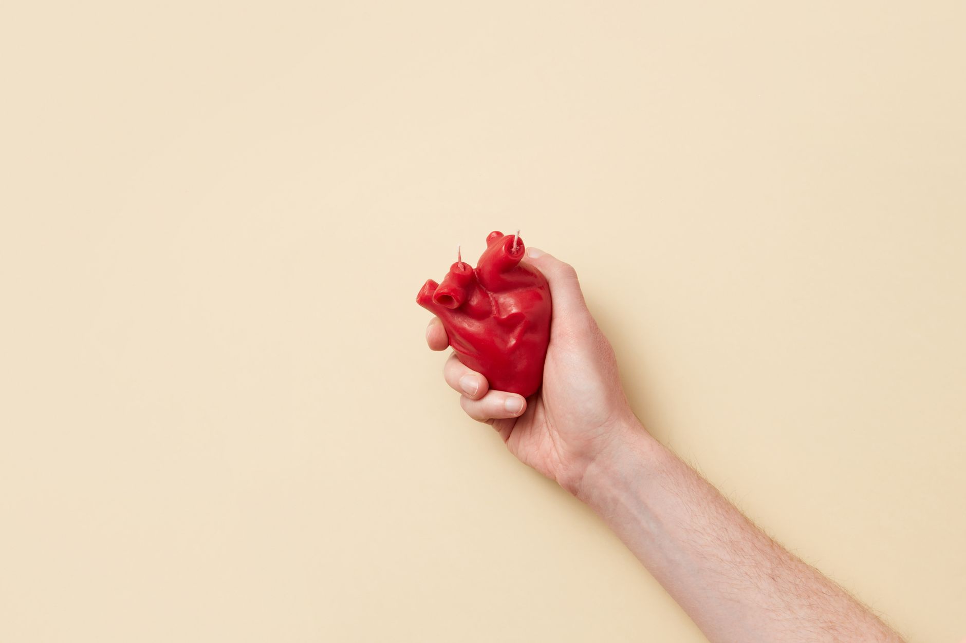 Main refermée sur un cœur en cire rouge, symbole de contraction