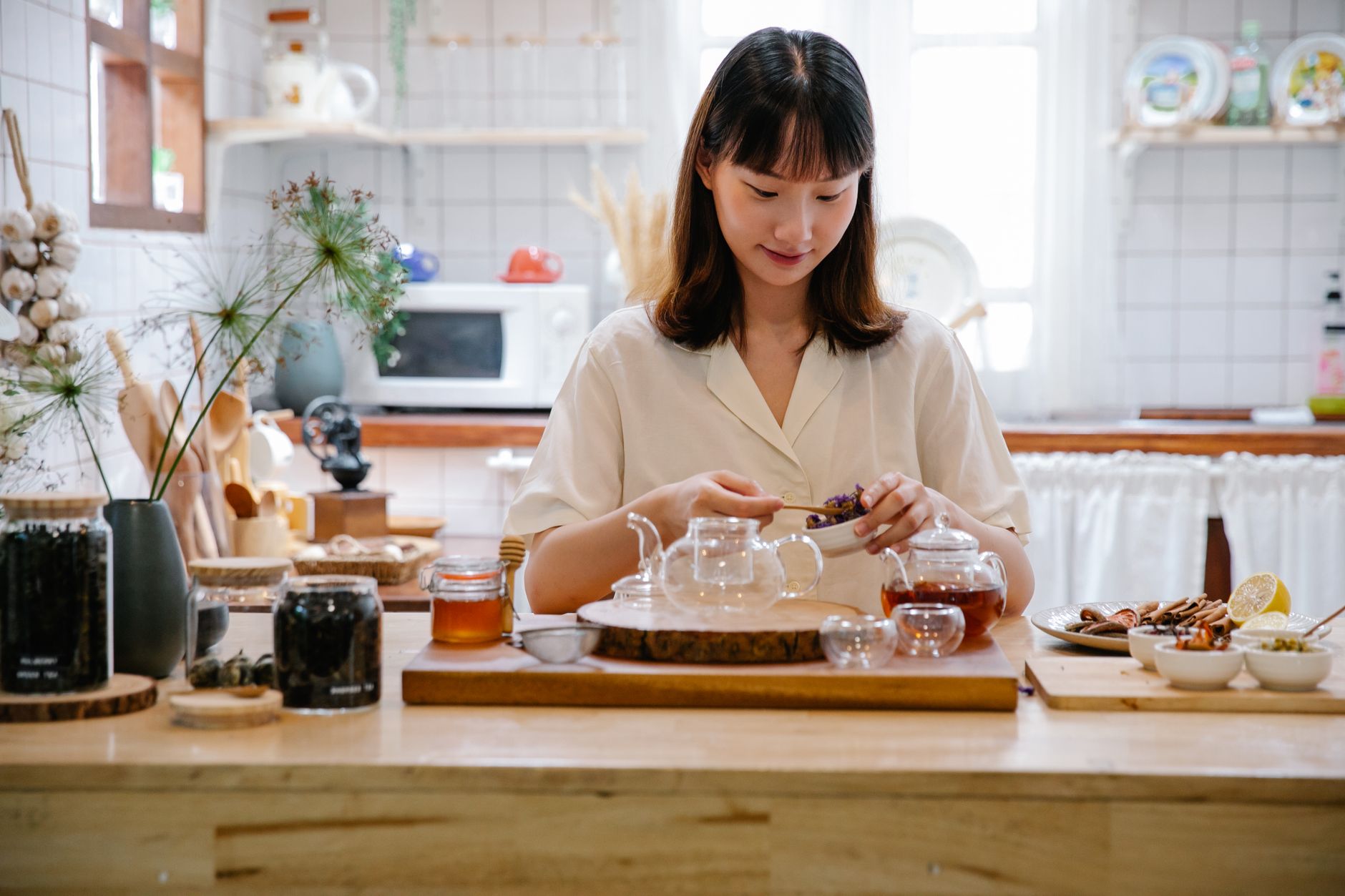 Femme préparant une tisane aux herbes dans une cuisine lumineuse