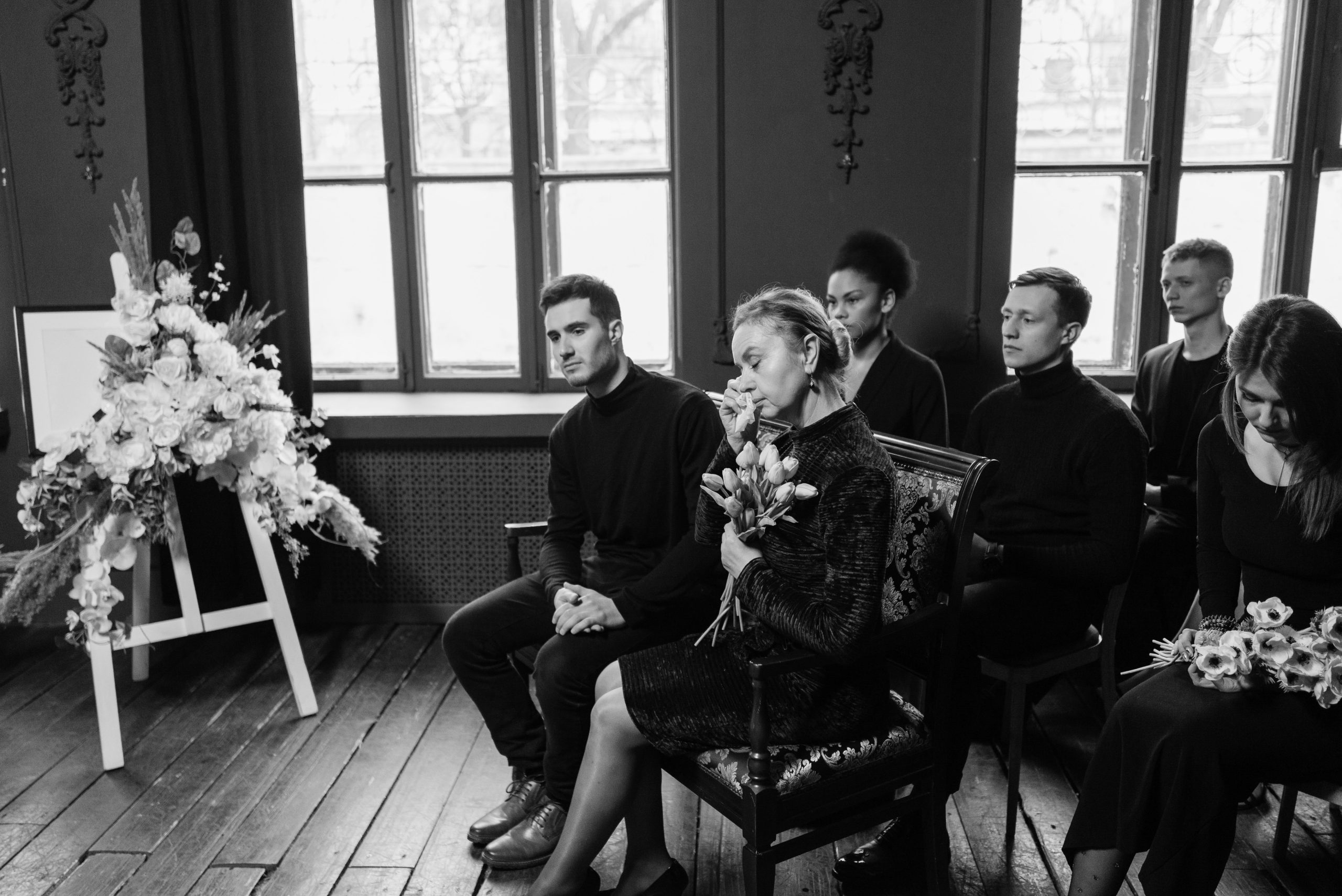 Grieving family members gather at a funeral, displaying emotions and support. Les membres de la famille endeuillés se rassemblent lors des funérailles, affichant des émotions et du soutien.