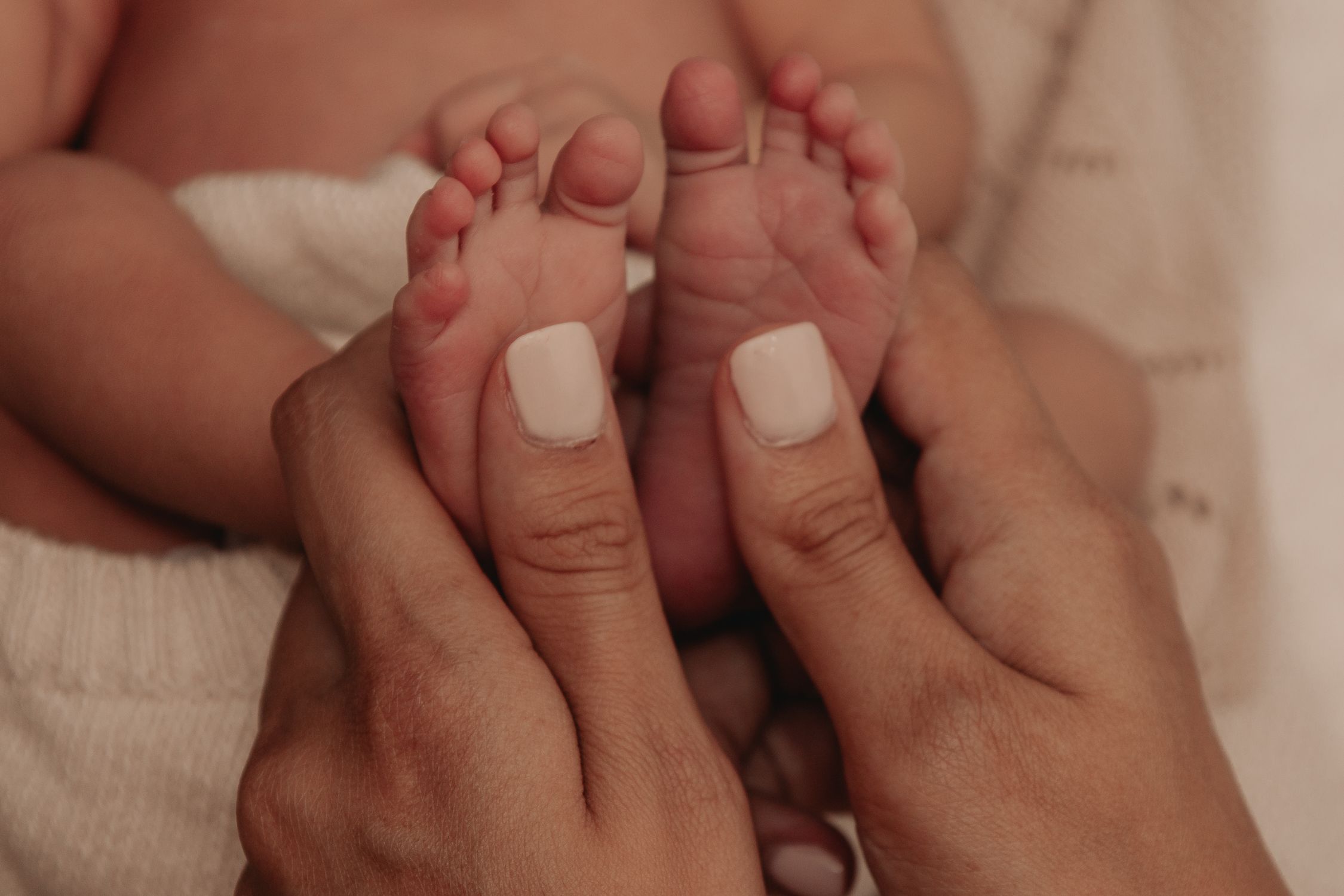 Gros plan sur les pieds d’un nouveau-né tenus par sa mère