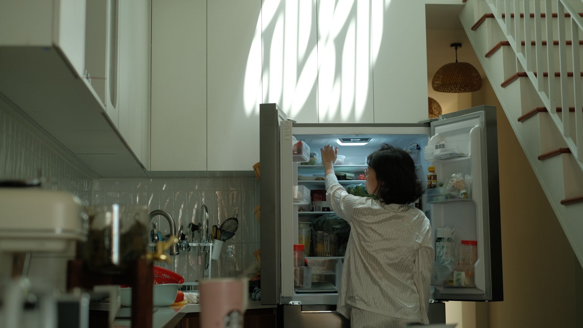 Femme qui ouvre un frigo dans une cuisine cosy