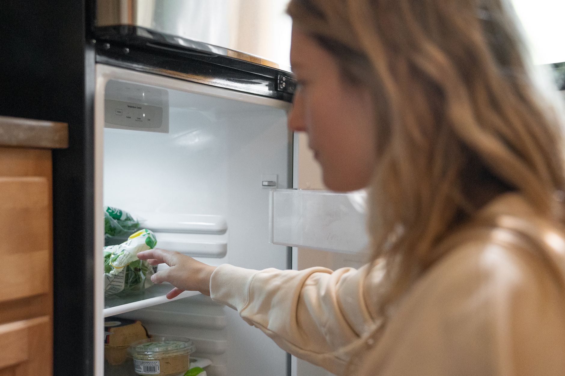 Femme qui range des légumes dans le frigo